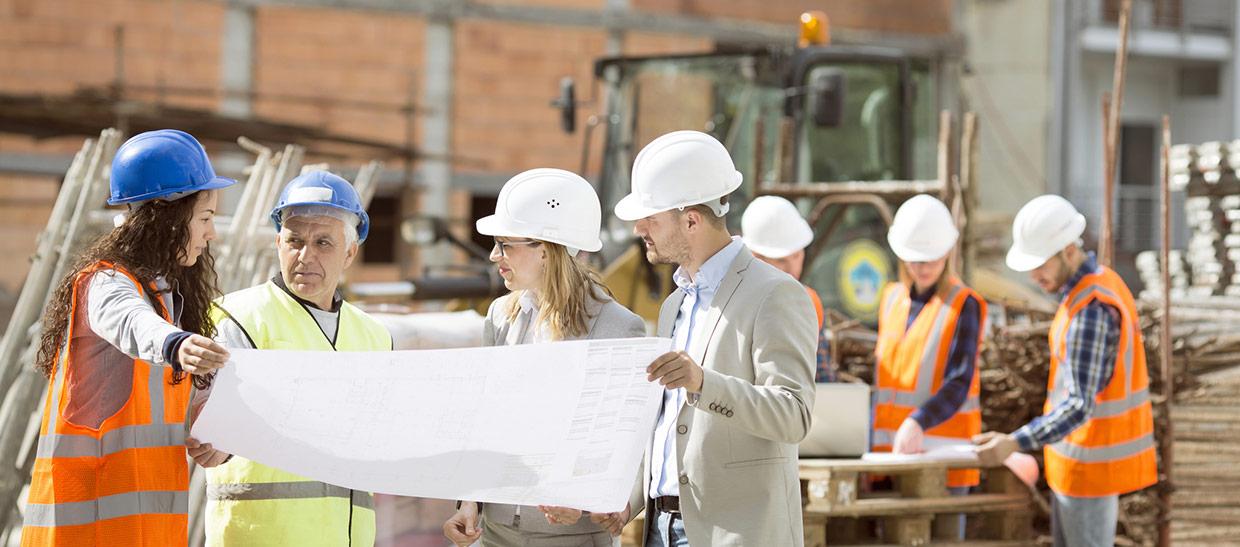 Project manager and employees reviewing blueprints at a job site