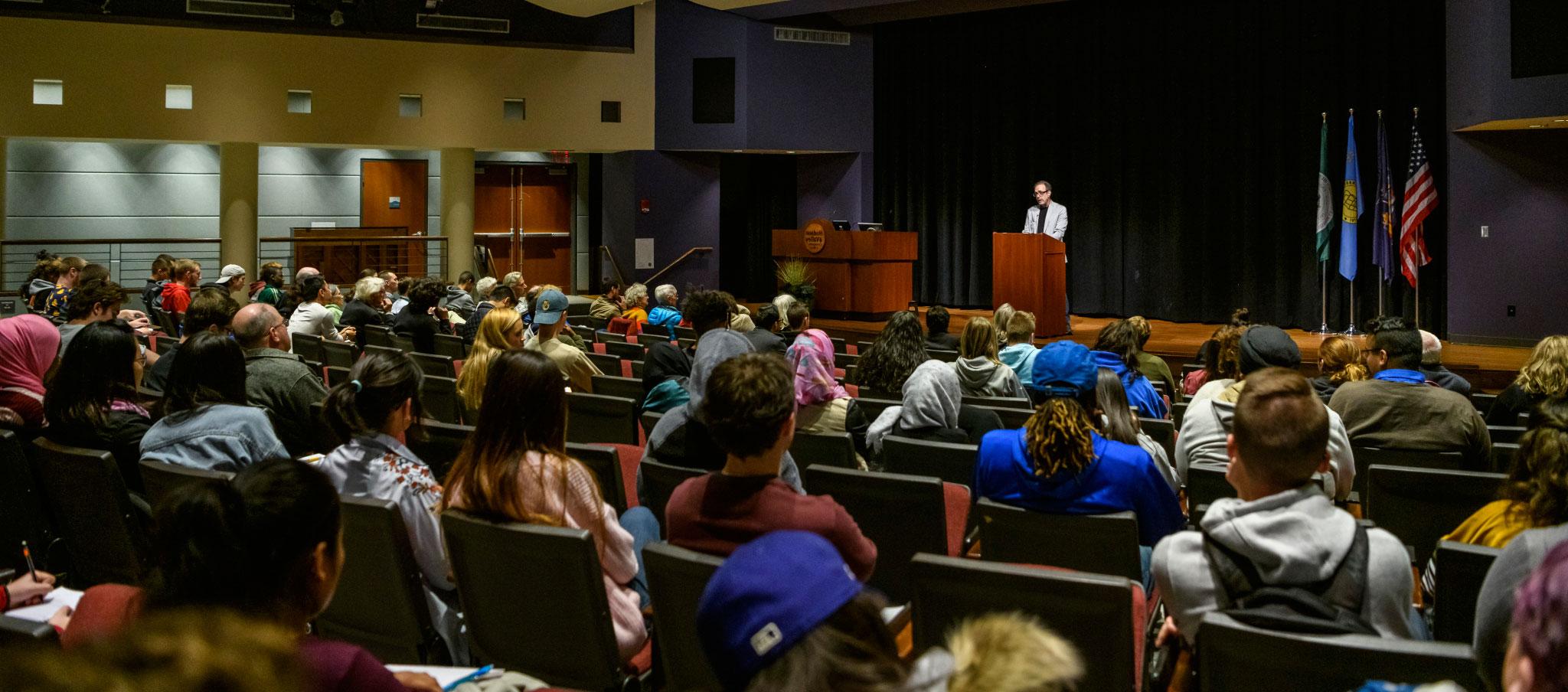 Students seated in the Bulmer Telecommunications Center Auditorium listening to a voices lecture