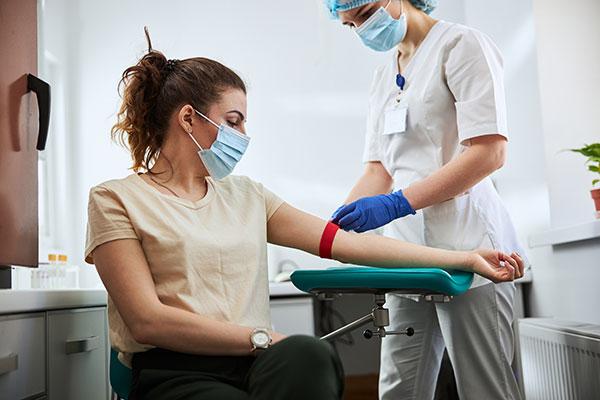 phlebotomy technician applying a tourniquet to a female patient arm
